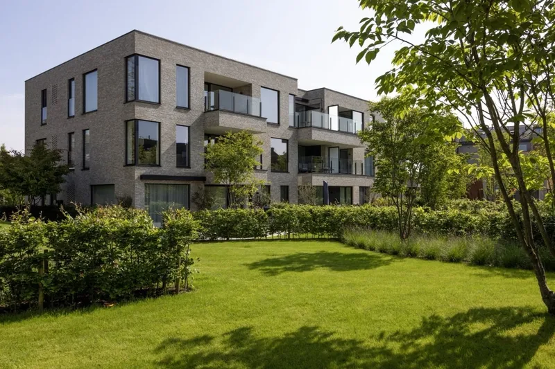 Brick apartment building overlooking a green lawn and garden borders at Maple Garden, Ghent
