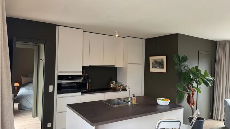 Open-plan Miele kitchen with island and stone worktop in a 74 m² Ghent apartment