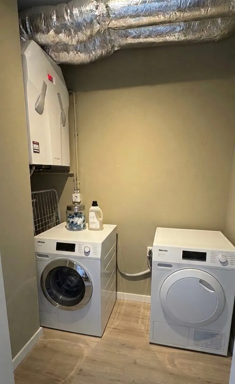Utility closet with a Miele washer and dryer in a Ghent furnished apartment